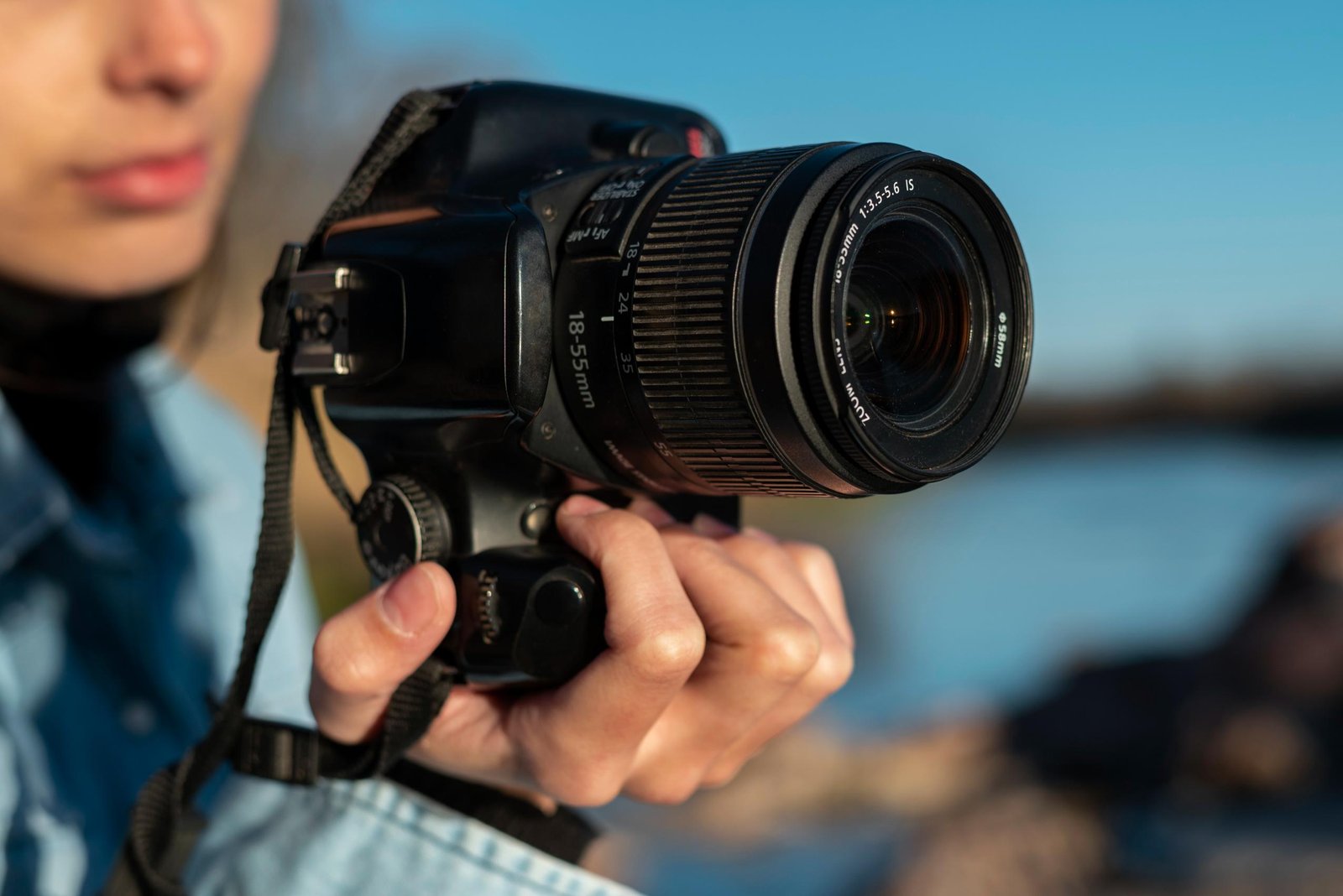 Une fille tenant un appareil photo avec un filtre photographie attaché à l'objectif