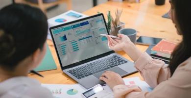 Femme analysant un tableau de bord Meta Ads sur ordinateur portable, montrant les performances de campagnes Facebook et Instagram avec graphiques, conversions et indicateurs de ROI dans un contexte de marketing digital.